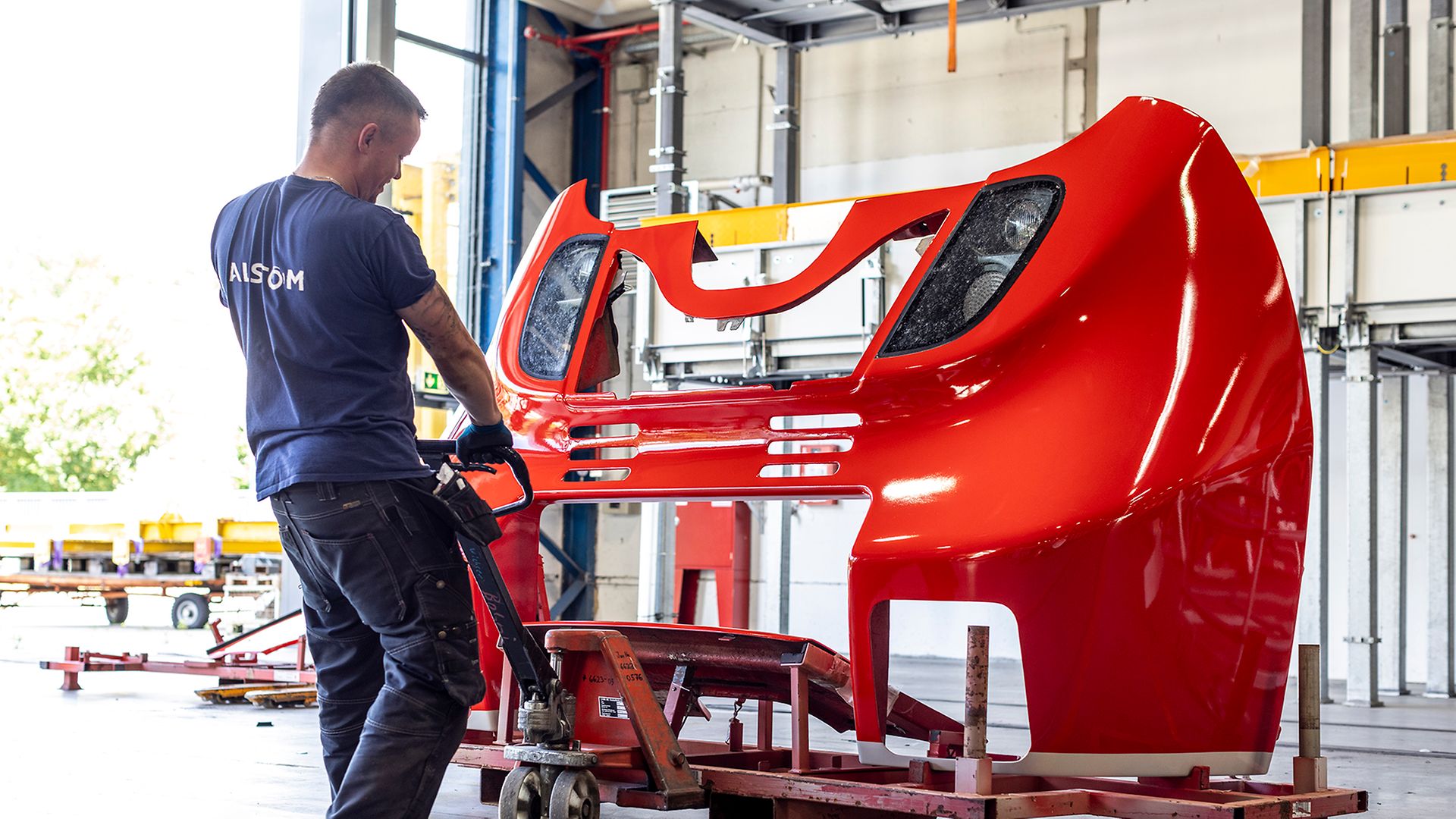 Ein Alstom-Mitarbeiter zieht die Frontverkleidung eines Zuges auf einem Hubwagen. 