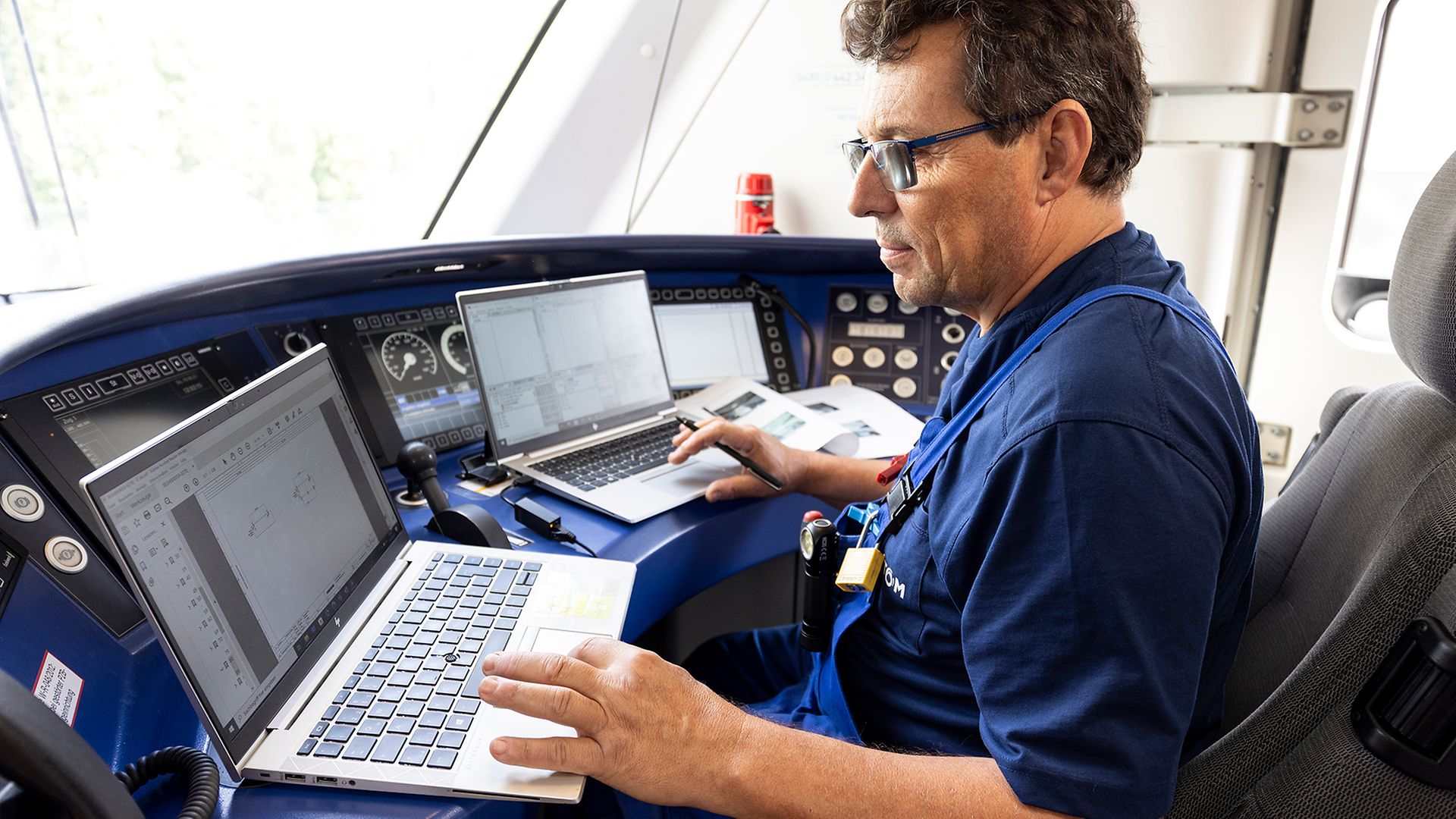 Ein Mitarbeiter von Alstom sitzt im Führerstand eines Zuges vor zwei Laptops.