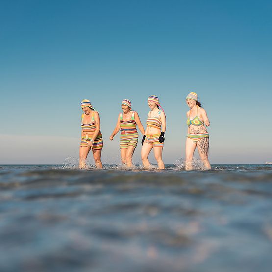 Vier Frauen in Nahaufnahme beim Baden mit Häkelmützen und Häkelbikinis