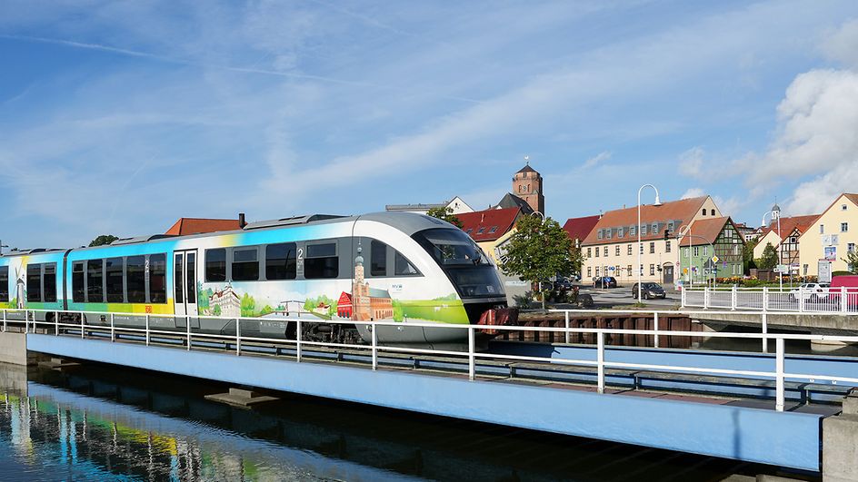 Ein mit Mecklenburg-Vorpommern-Motiven gestalteter Zug fährt über eine Brücke in Wolgast.