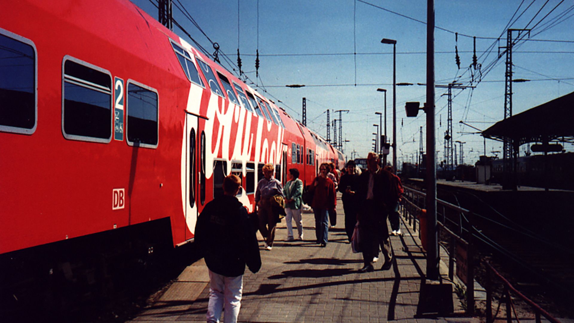 Ein S_Bahn-Zug mit aufgedruckter Coca-Cola-Werbung am Bahnhof