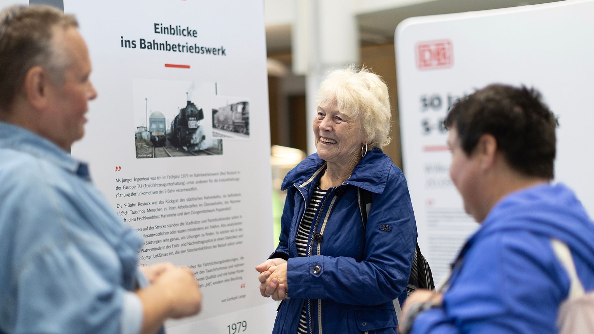 Drei Menschen im Grspräch vor einer der Ausstellungstafeln