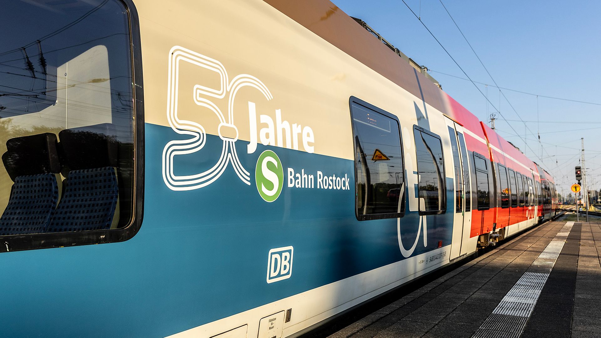 Ein moderner S-Bahn-Zug zeigt eine der historischen Farbgebung der S-Bahn nachempfundene Beklebung in beige, blau und braun.