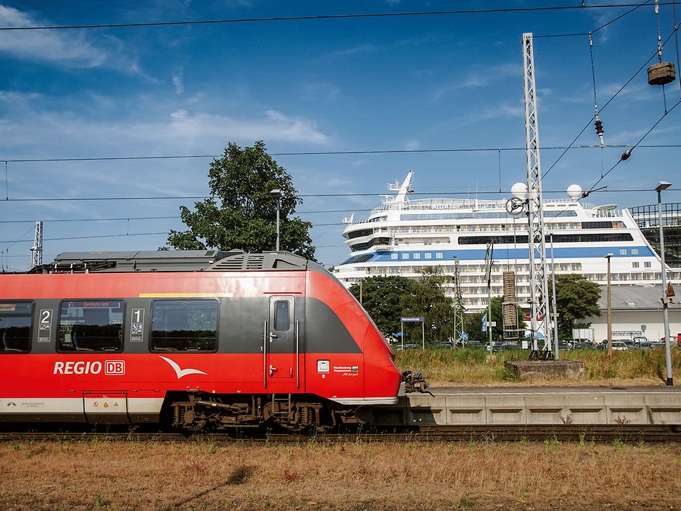 Talent2-Triebwagen in Warnemünde, im Hintrergrund ein Kreuzfahrtschiff. 