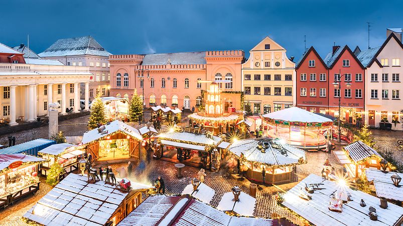 Historische Gebäude umrahmen hell erleuchtete Buden des Weihnachtsmarktes auf dem Marktplatz von Schwerin 