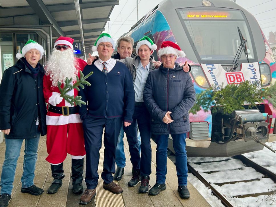 Eine Gruppe von Männern mit Nikolaus-Mützen am Bahnsteig in Neustrelitz vor dem „Nikolaus-Express“